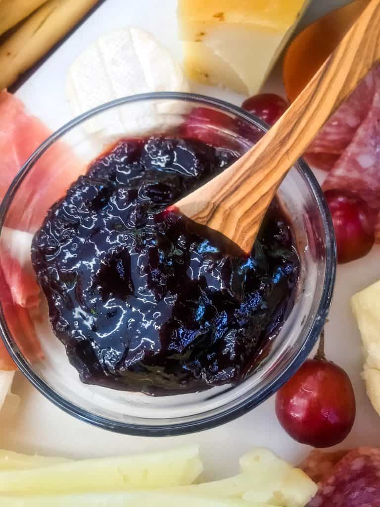 A small bowl of jam with a wood spoon