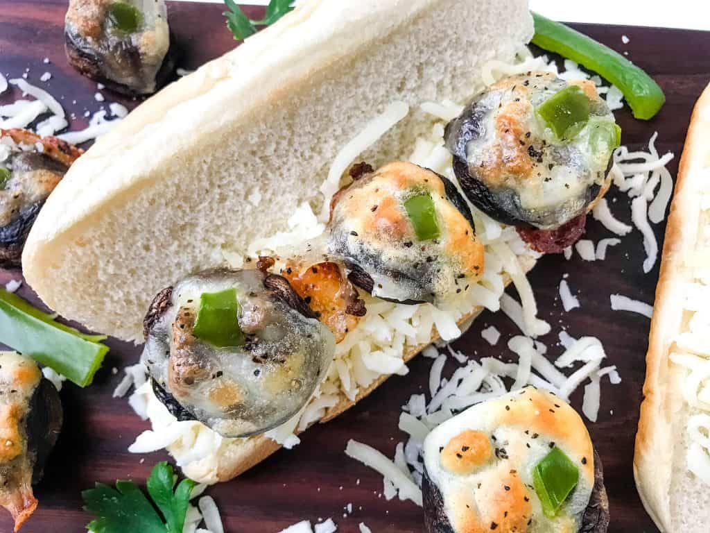 A bun filled with shredded mozzarella and three Philly Cheesesteak Stuffed Mushrooms