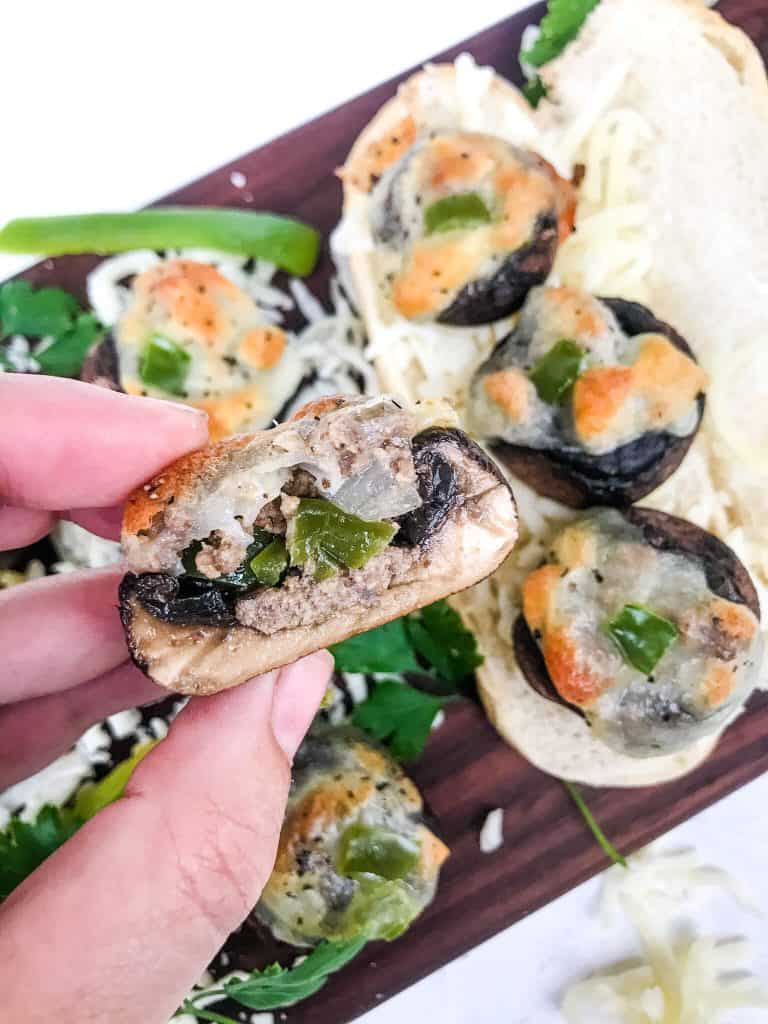 A hand holding half of a Philly Cheesesteak Stuffed Mushroom