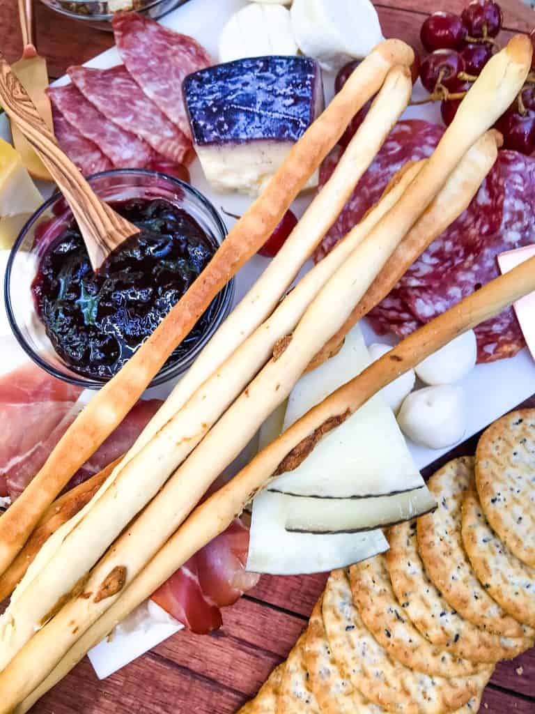 Roasted Garlic Grissini (Italian Breadsticks) laying across a charcuterie board