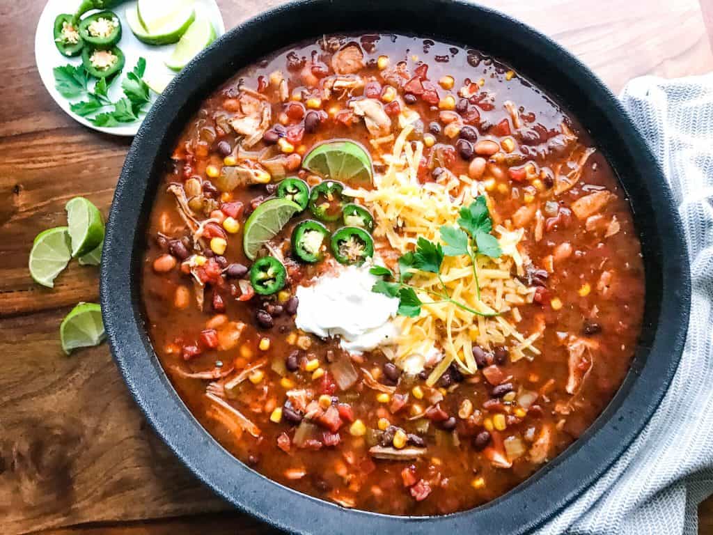 A large black bowl filled with Mexican soup on a wood table