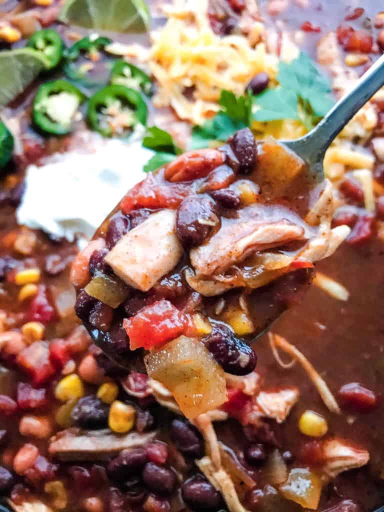 A spoon scooping Chicken Taco Soup out of a large bowl