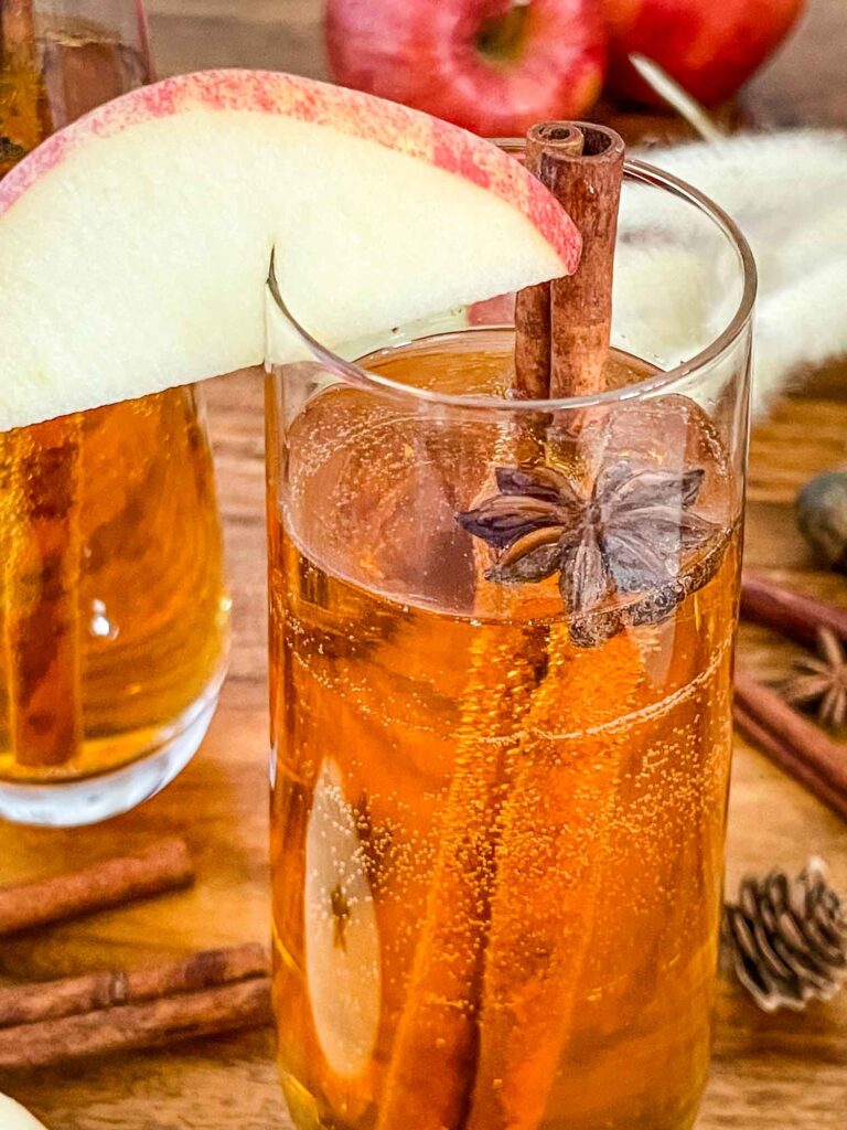 Close view of a Cinnamon Apple Cider Mimosa with an apple wedge on the rim.