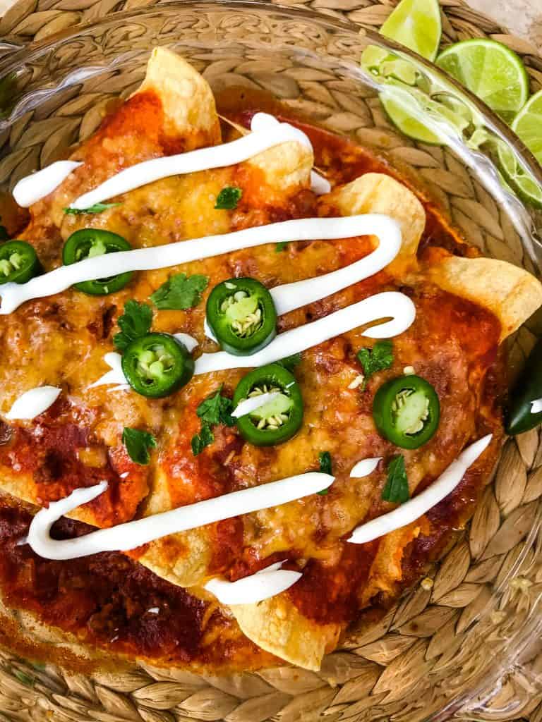 Ground Beef Enchiladas in a dish with sour cream and jalapenos on top