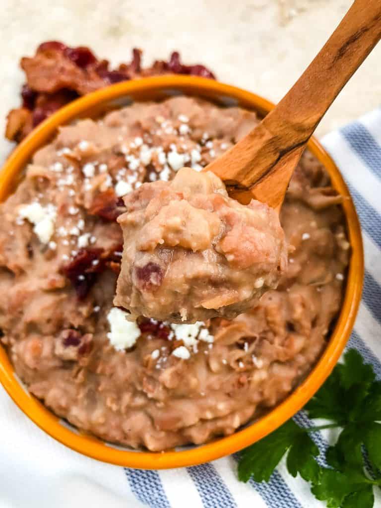 Wooden spoon holding Homemade Bacon Refried Beans