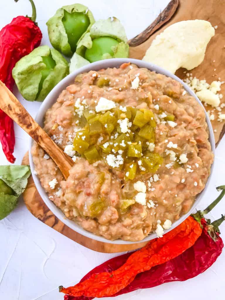 Bowl of Homemade Hatch Green Chile Refried Beans topped with peppers and cheese