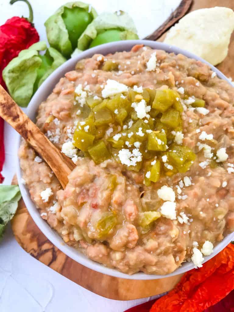 Homemade Hatch Green Chile Refried Beans in a bowl with a wood spoon