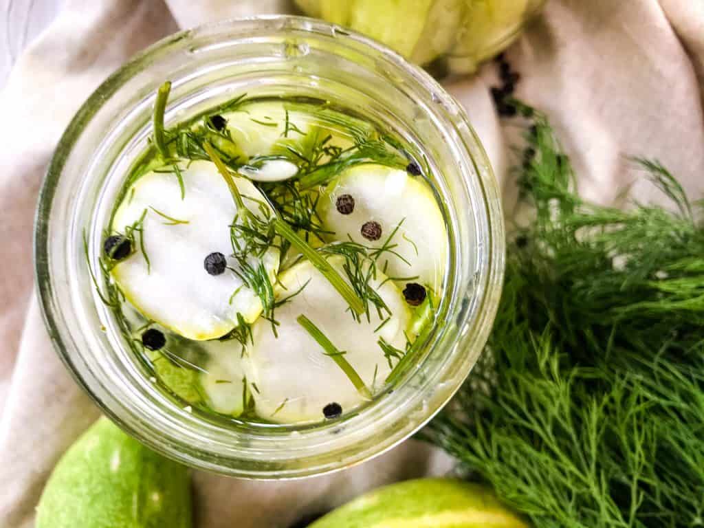 Homemade Peppercorn Dill Pickles in a jar from the top view with dill next to it