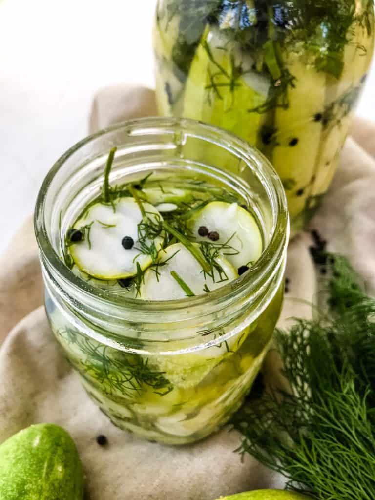 Two jars of Homemade Peppercorn Dill Pickles on a towel