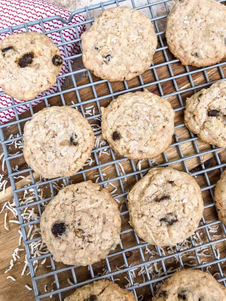 Chewy Coconut Oatmeal Raisin Cookies with Walnuts cooling on a wire rack above a cutting board