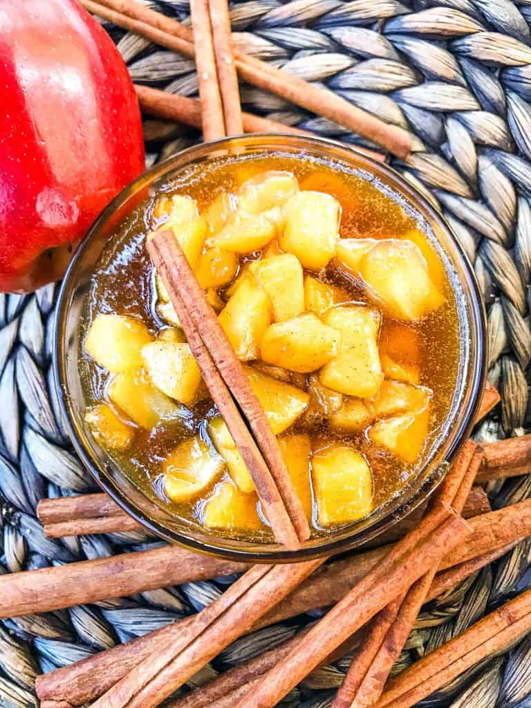 Cinnamon Apple Dessert Sauce surrounded by an apple and cinnamon sticks