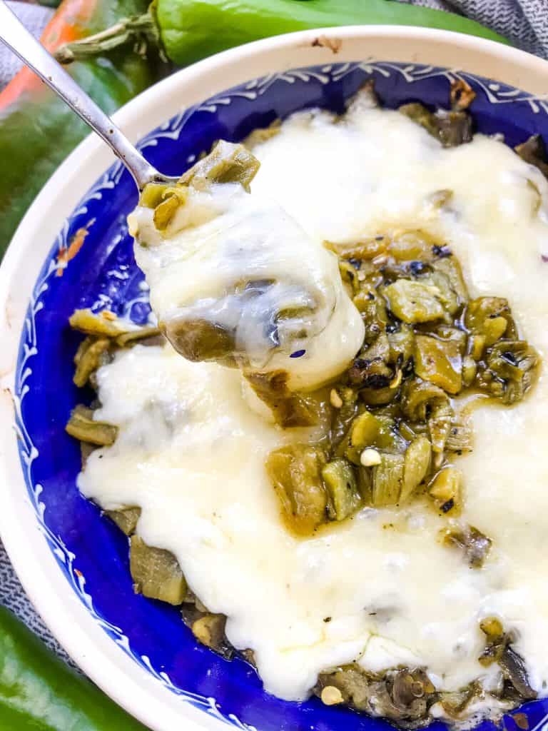 A spoon scooping out Hatch Green Chile Queso Fundido from a dish