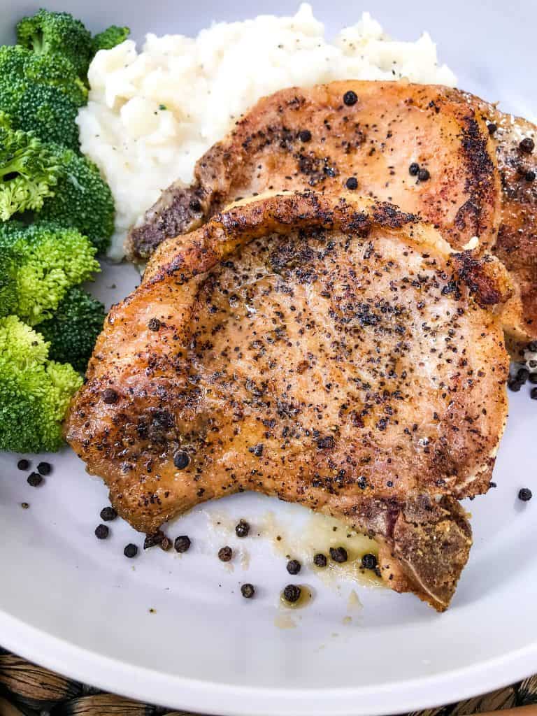 Peppercorn Garlic Pork Chops on a plate with broccoli and mashed potatoes