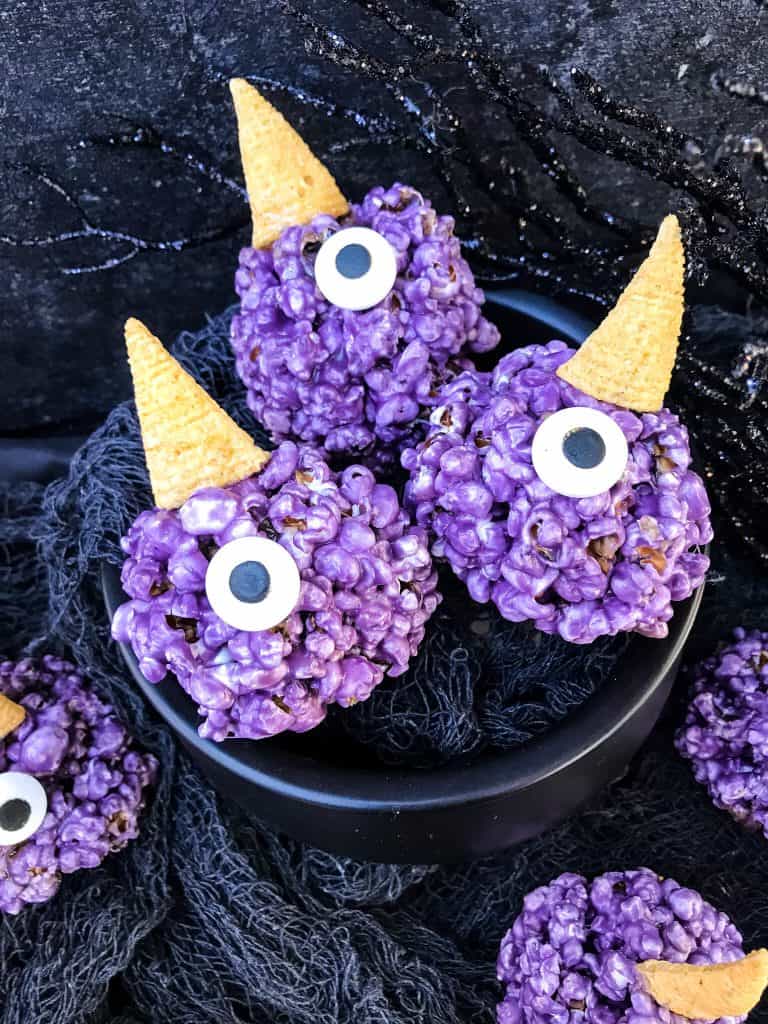 A cauldron with three Purple People Eater Halloween Popcorn Balls