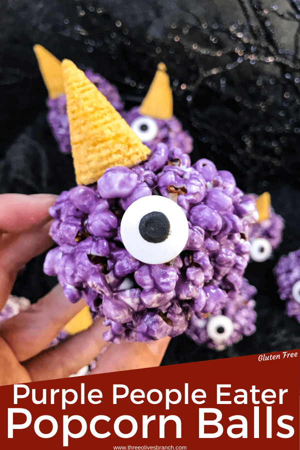 Pin image of hand holding Purple People Eater Halloween Popcorn Balls with title at bottom