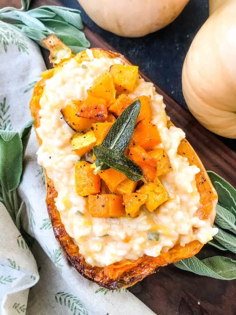 Butternut Squash Sage Risotto in a squash half and topped with squash cubes and sage.