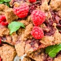 A close up of one Chocolate Raspberry Crumble Bar with fresh raspberries