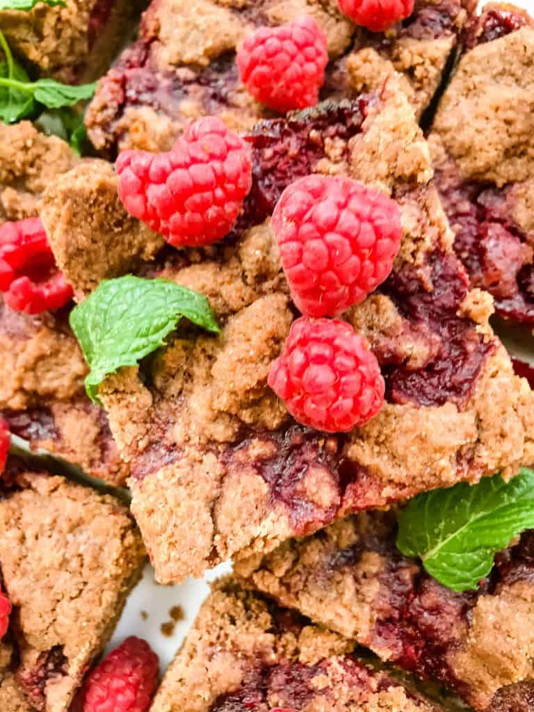 A close up of one Chocolate Raspberry Crumble Bar with fresh raspberries