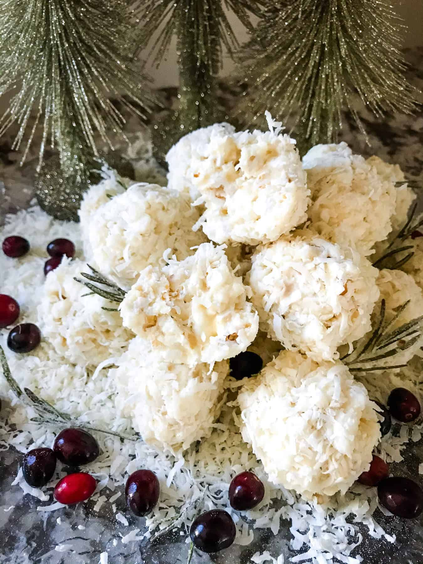 A plate with a stack of Snowball Popcorn Balls surrounded by cranberries