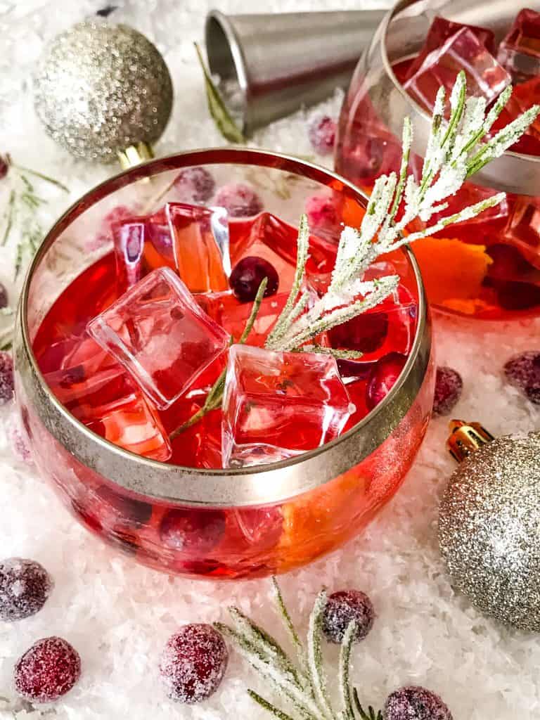 Top view of red cocktail with rosemary and cranberries in it