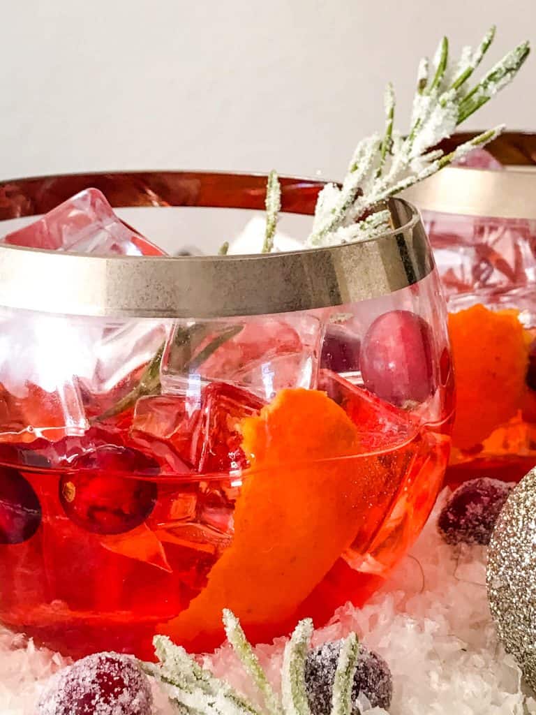 Close up of Cranberry Old Fashioned Cocktail in round clear glass with silver tim