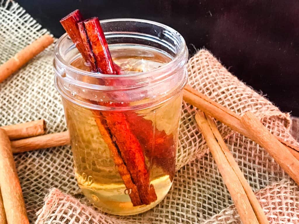 A jar of syrup with cinnamon around it