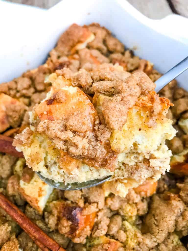 A spoon scooping Overnight Eggnog French Toast Casserole out of the dish