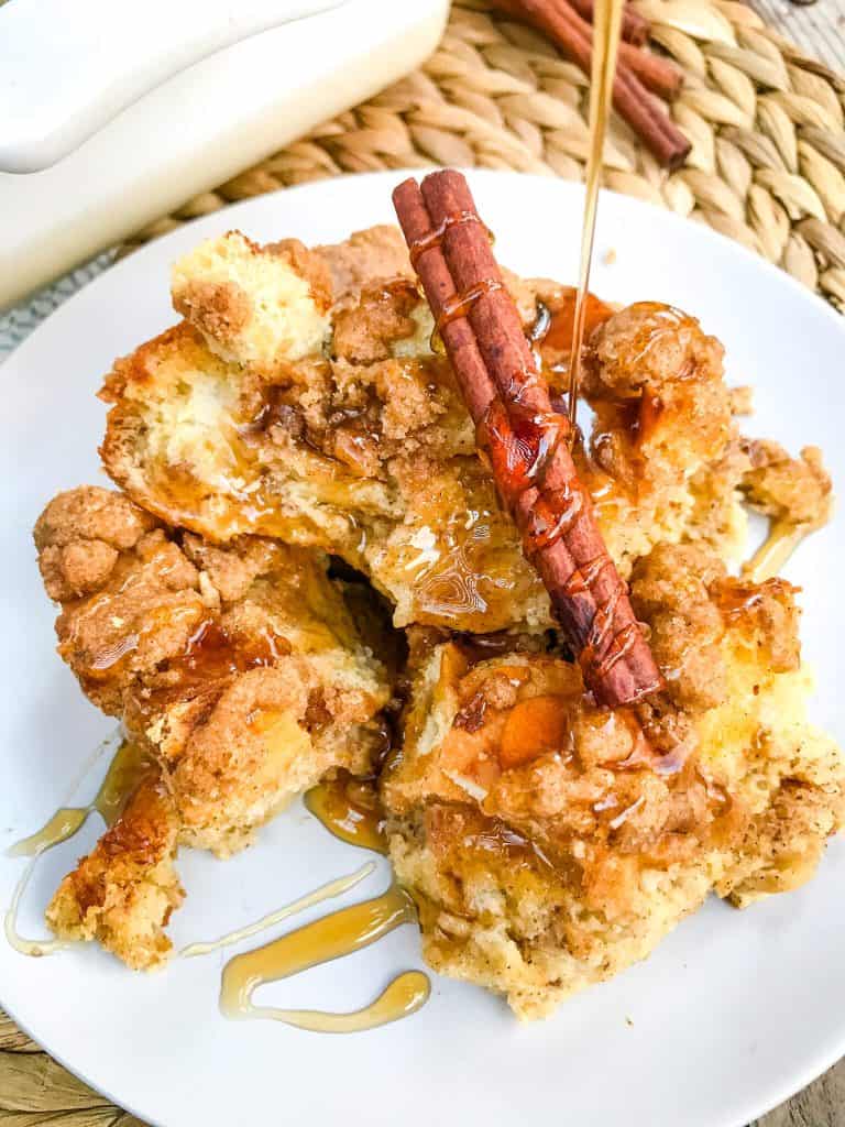 Syrup pouring on a plate of Overnight Eggnog French Toast Casserole