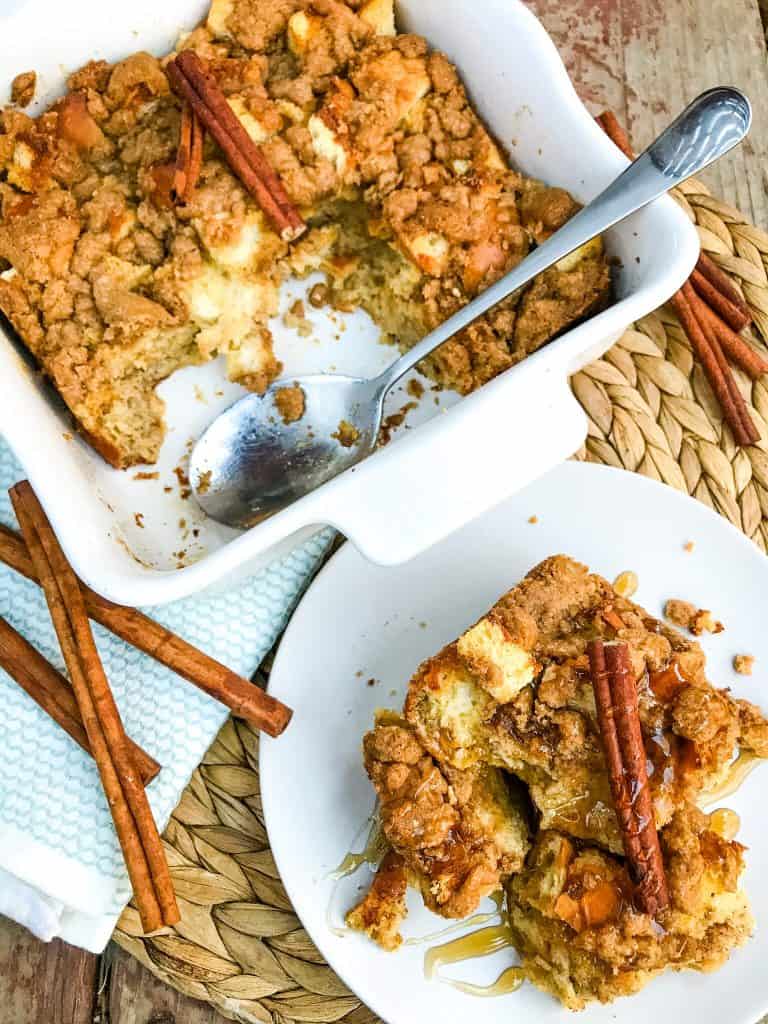 A plate of Overnight Eggnog French Toast Casserole with the serving dish next to it on a woven mat