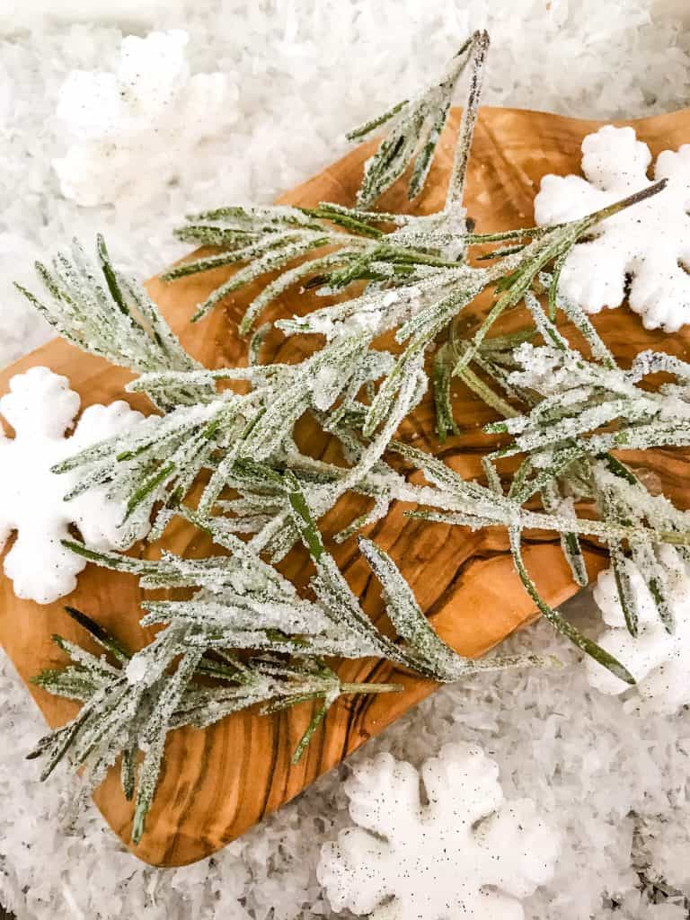 Frosted herbs with snow around it on a cutting board