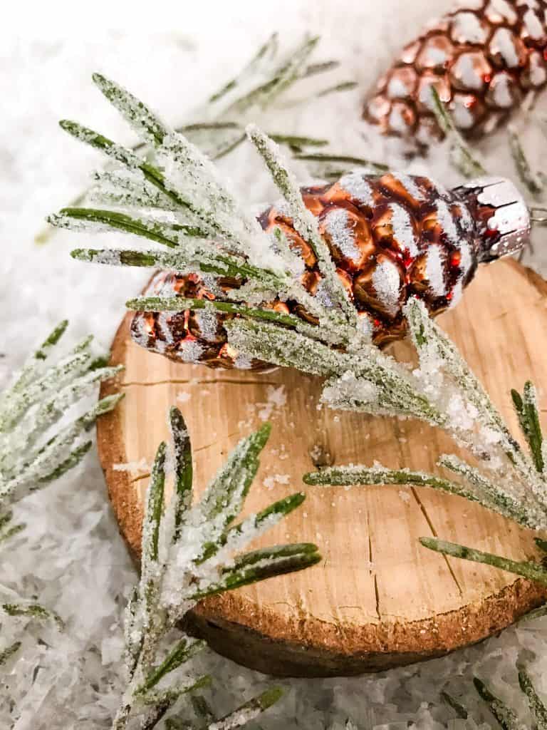 Sparkling Rosemary (Sugared Rosemary) on a slice of wood with a pinecone ornament