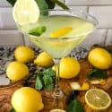 A martini glass full of Amalfi Martini Limoncello surrounded by lemons and mint