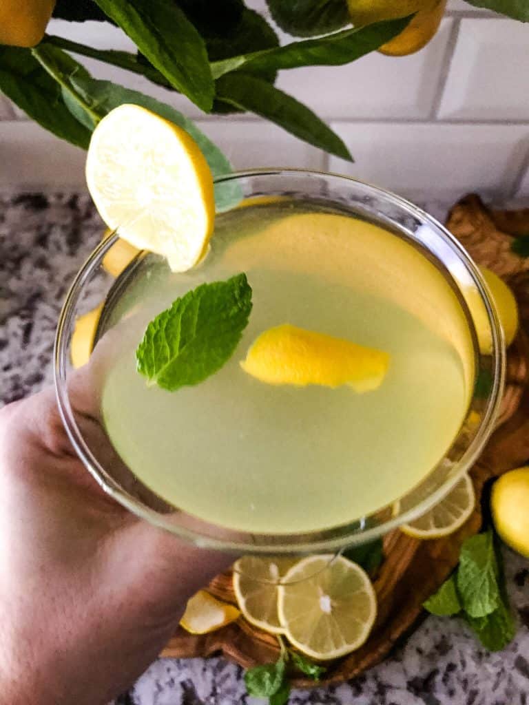 A hand holding a lemon martini with view from the top