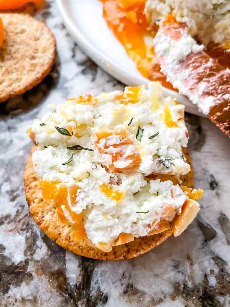 A close up of a cracker with the goat cheese mixture on it