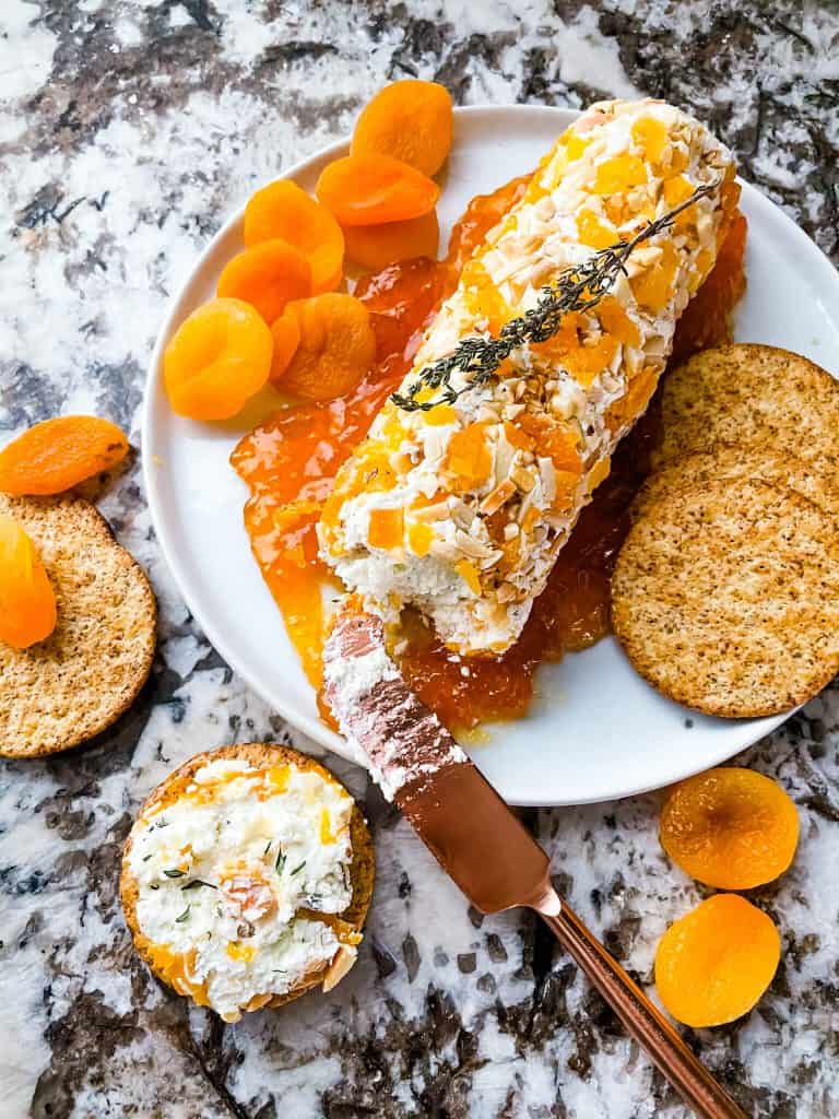 Apricot Almond Goat Cheese Log sliced into with some cheese on a cracker