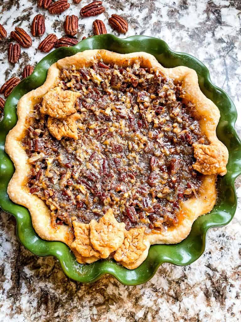 A full Chocolate Bourbon Pecan Pie in a green pie dish from the top