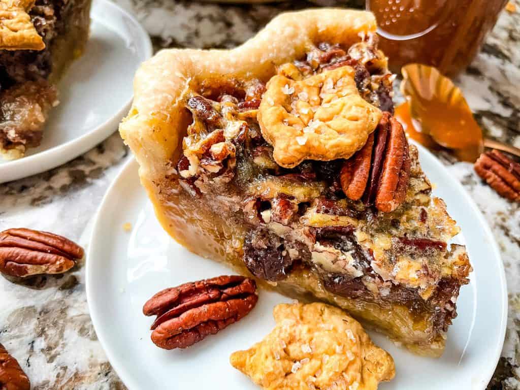 A slice of Bourbon Chocolate Pecan Pie on a small plate from the side view