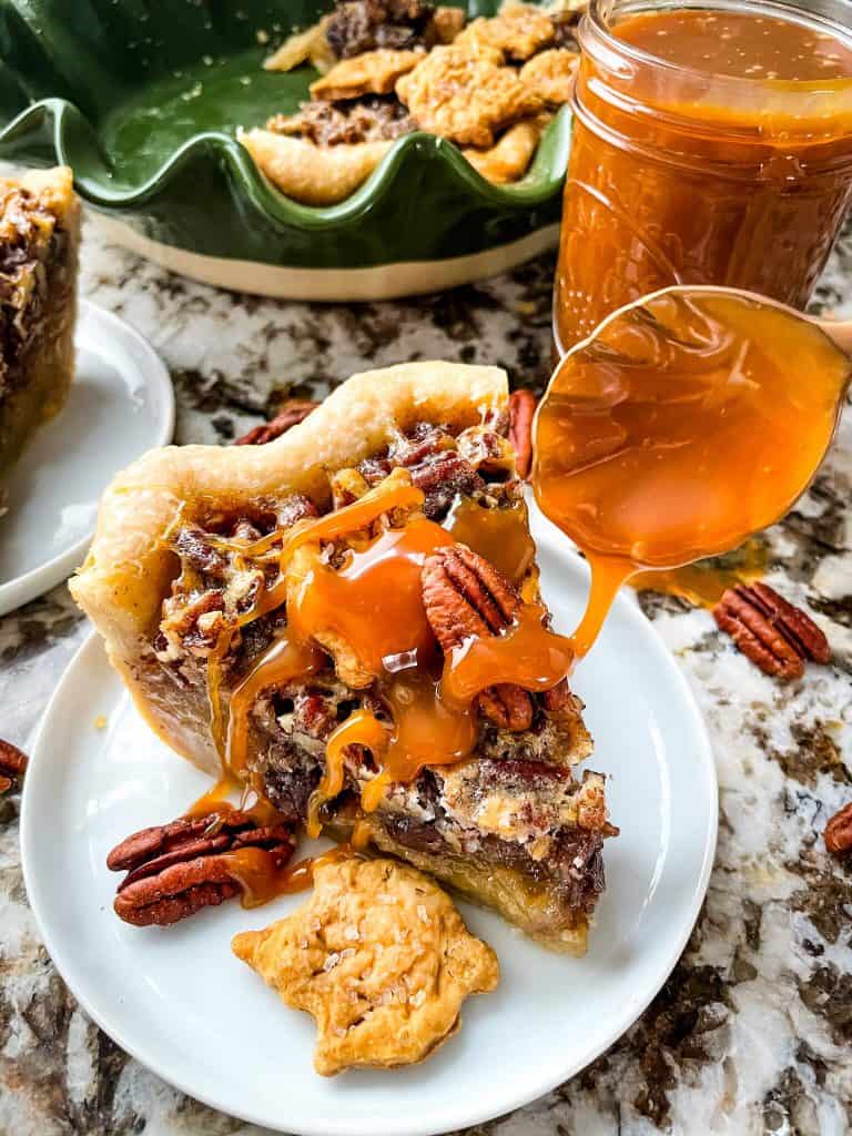 Pecan pie slice with caramel sauce being poured over it