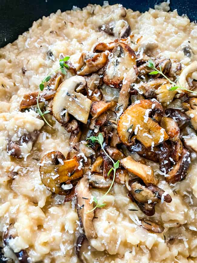 Close up of Creamy Mushroom Risotto in a black bowl topped with mushrooms
