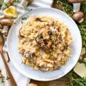 Creamy Mushroom Risotto on a white plate surrounded by mushrooms and fresh thyme
