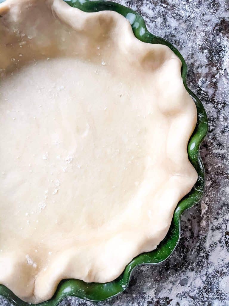 Close up top view of half an empty pie crust in a green fluted dish