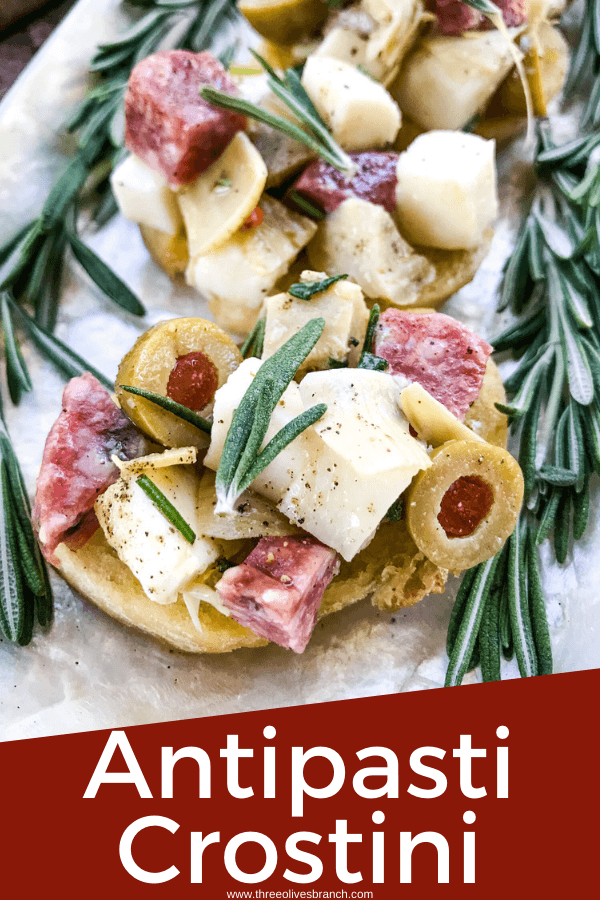 Pin image for Antipasti Crostini on a platter with rosemary and title at bottom