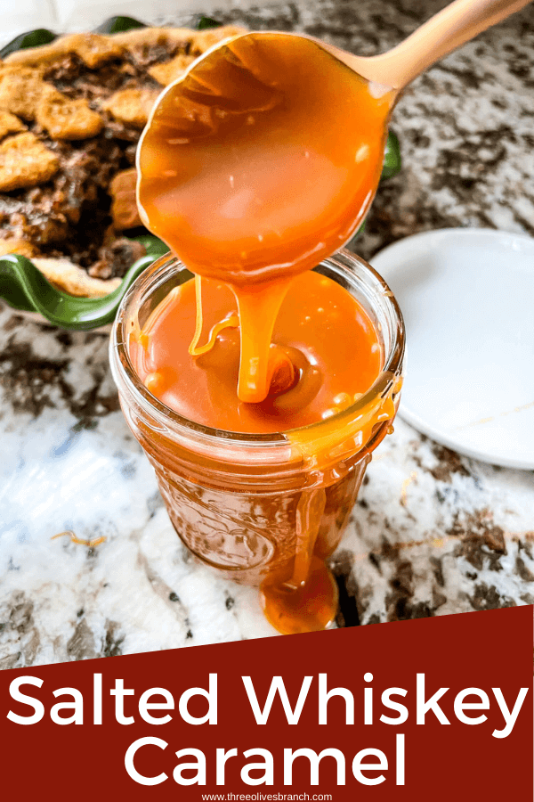 Pin image for Salted Whiskey Caramel Sauce being poured in a glass jar by a copper spoon with title at bottom