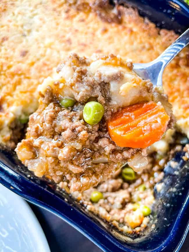 A spoon scooping the cottage pie out of a blue dish