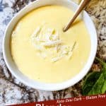 Pin image for Blender Parmesan Cheese Hollandaise Sauce of a spoon scooping some sauce out of a white bowl