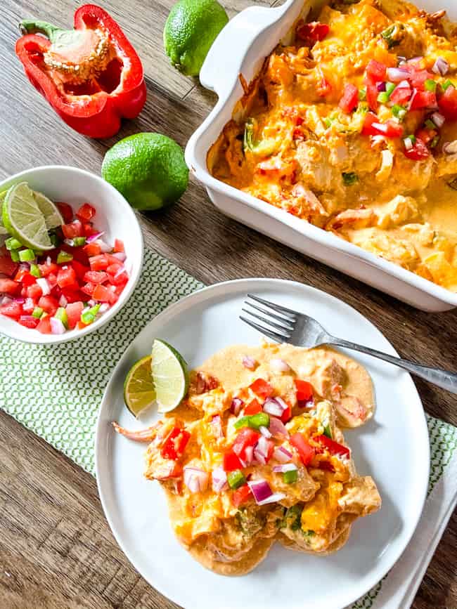 The meal in a baking dish and on a plate with limes and salsa next to it