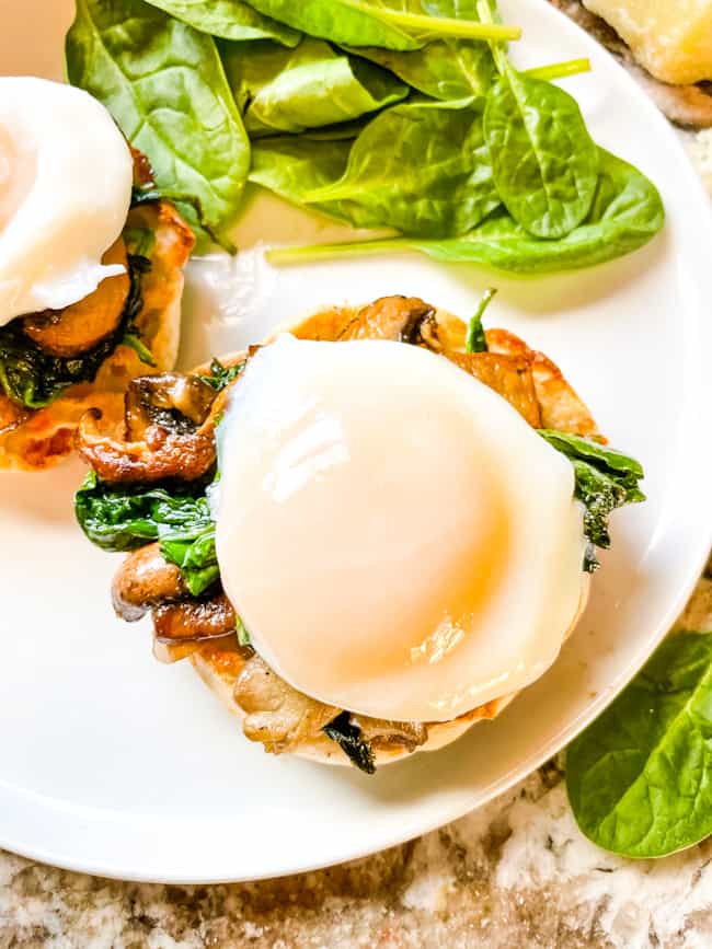 A poached egg on top of eggs benedict stack