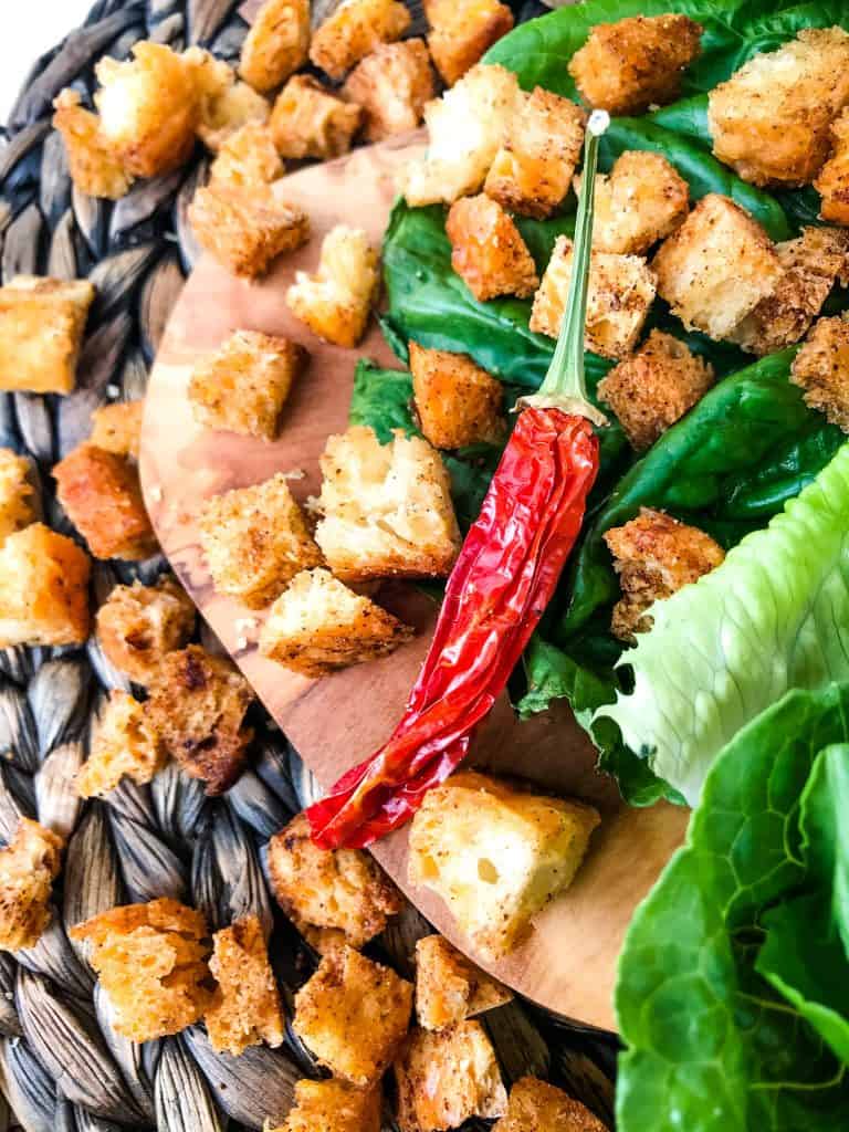 Croutons scattered on a board with a pepper
