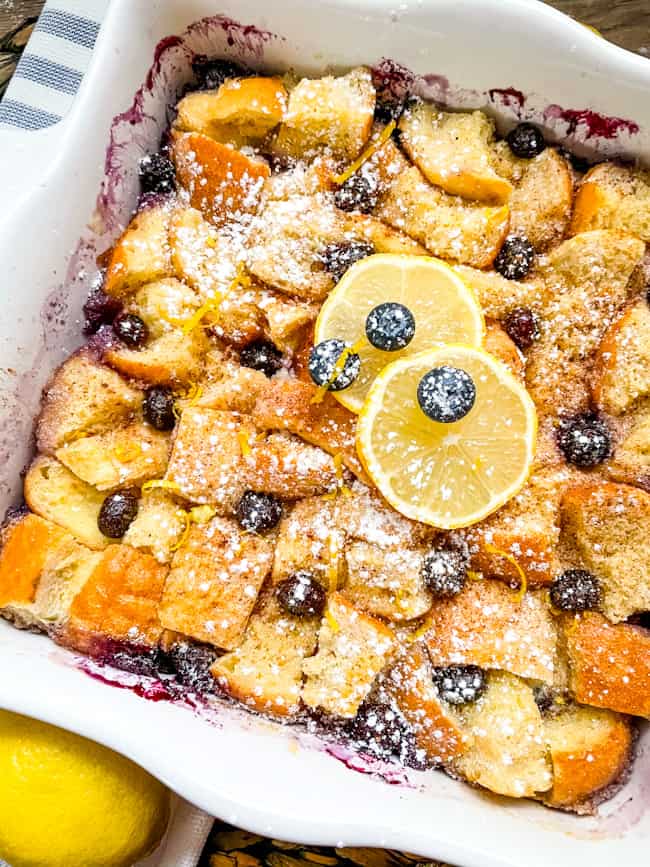 A white dish full of pudding with berries and powdered sugar