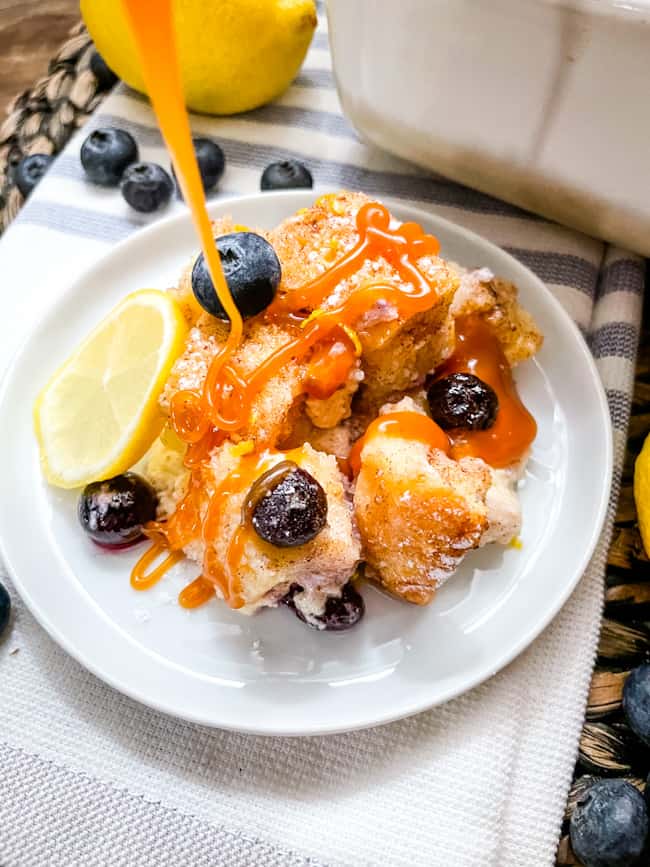 Caramel sauce being poured on a plate of bread pudding